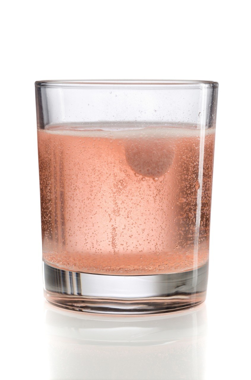 A glass of fizzing VitalFactors next to the VitalFactors box on a kitchen counter